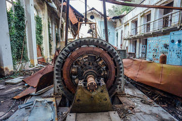 Ruined abandoned hydroelectric power plant. Rusty generator at machinery. Demolished roof. Gagra, Abkhazia