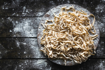 Italian traditional tagliatelle on the wooden background with blank space