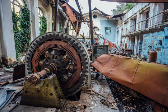Ruined abandoned hydroelectric power plant. Rusty generator at machinery. Demolished roof. Gagra, Abkhazia