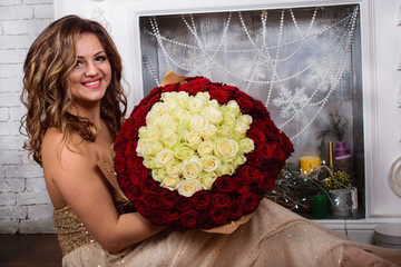 beautiful girl in a long dress with a gorgeous bouquet of roses on a background of fireplace