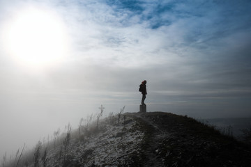 silhouette of a mountaineer standing on the top of mountain - winter and sunshine