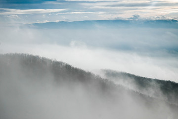 Fototapeta premium foggy mountain slope in winter with clouds and sunshine