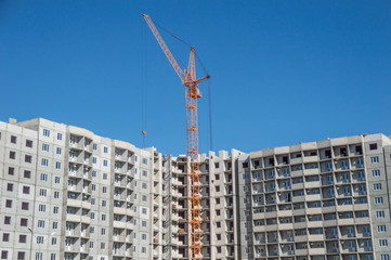 Fototapeta na wymiar Multistorey housing under construction and highrise cranes