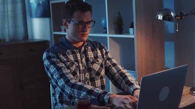 Freelancer working hard late at night. Making money, modern times, contemporary technologies. Daily routine. Slow motion, camera stabilizer shot, male portrait