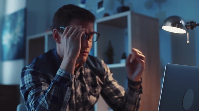 Young worker falls asleep on his workplace then gets up. Working hard, making money, income. Modern lifestyle, business. Slow motion, camera stabilizer shot, male portrait