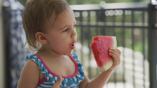 Young girl eating watermelon at backyard barbeque