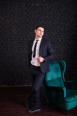Handsome man in a business suit against a black brick wall, model photo. Succesful fashionable man