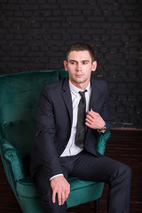 Fototapeta na wymiar Handsome man in a business suit against a black brick wall, model photo. Succesful fashionable man