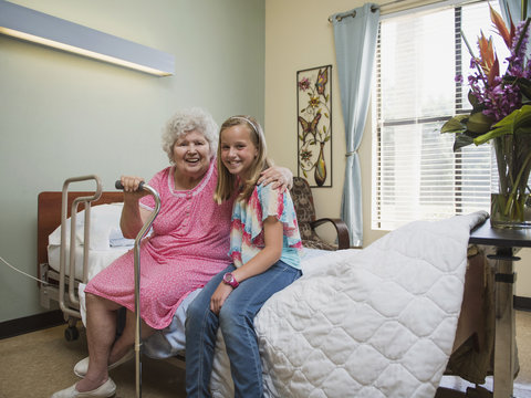 Smiling Caucasian woman sitting on bed with granddaughter