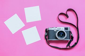 Vintage photo camera on Valentine's Day pink background with composition of blank photo frames,...