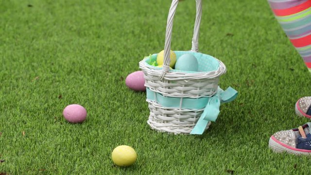 Young girl picking up Easter eggs in grass and putting them into basket