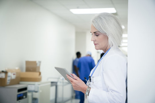 Doctor leaning on wall using digital tablet