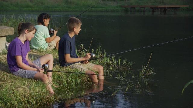 Kids at summer camp fishing in pond