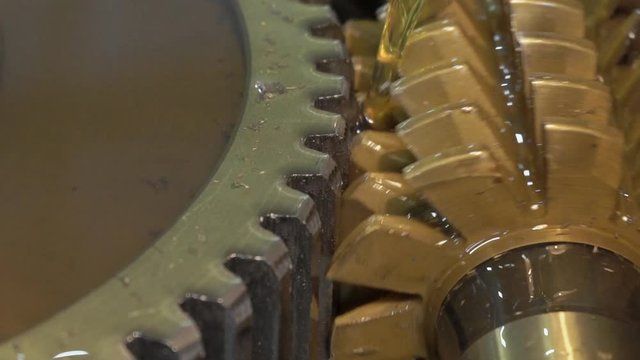 Big alluminium gear is being cut on the special machine on watch plant. Metall circle is turning aroung and nicks are being made by the iron equipment with small cutters, which is twisting contr