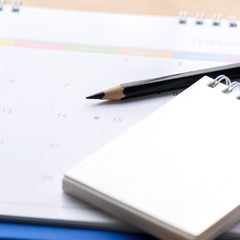 Notepad with pencil, calendar  on wood board blurry background.using wallpaper for education, business photo.Take note of the product for book with paper and concept, object or copy space.