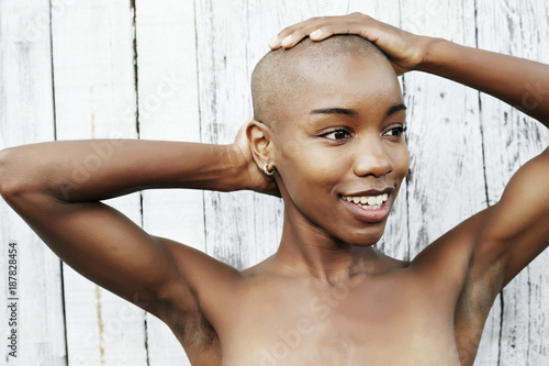 Close up of naked black woman rubbing bald head\