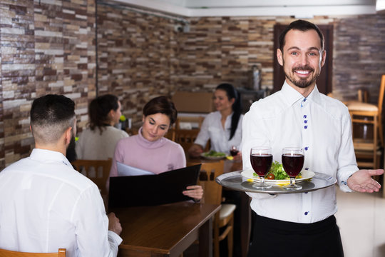 Waiter welcoming guests in restaurant