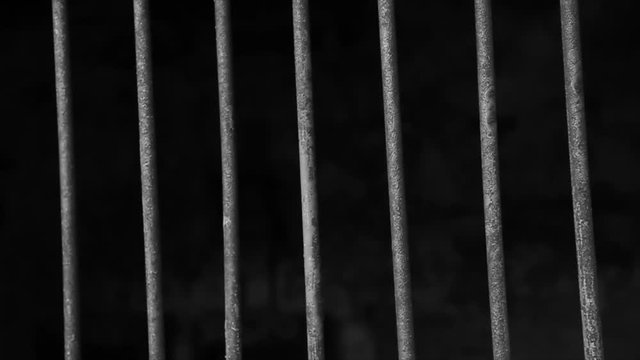 Jail or prison cell. Obsolete gray grunge concrete room. Iron baluster or steel Cage. Old prison bars cell lock background dark black and light