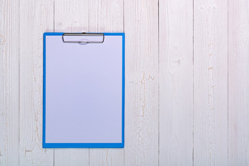 clipboard with blank white paper sheet on wood table top view with copy space.