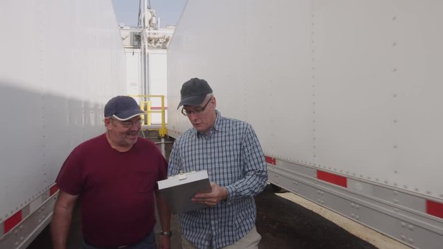Truck drivers looking over clipboard together.  Fully released for commercial use.