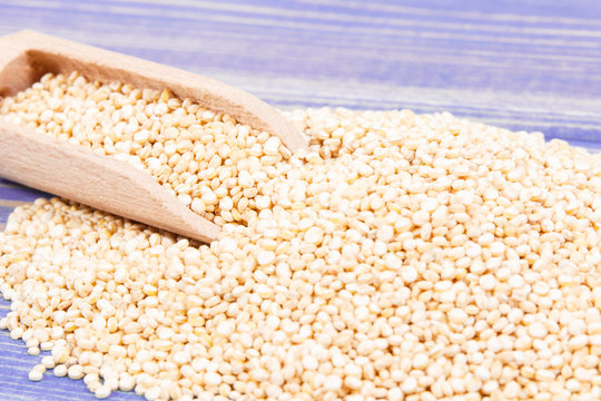 Heap of quinoa seeds with wooden scoop as source healthy vitamins