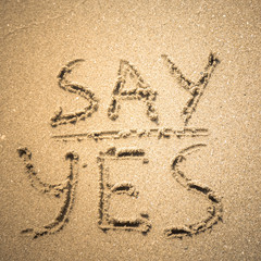 Say Yes word is written on the beach sand