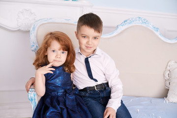 Brother and sister. Bright interior. Blue dress. Horizontally