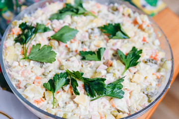Olivier salad decorated with greens in a large bowl