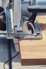 Close up electric saw to sawing wood board, solf focus.