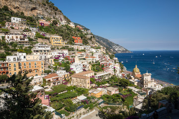 Fototapeta premium Kolorowe Positano, klejnot Wybrzeża Amalfitańskiego, z wielobarwnymi domami i budynkami wznoszącymi się na dużym wzgórzu z widokiem na morze. Włochy