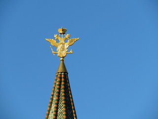 Fototapeta na wymiar Golden double-headed eagle on the top of the tower in Moscow. The national emblem of Russia on the background of blue sky