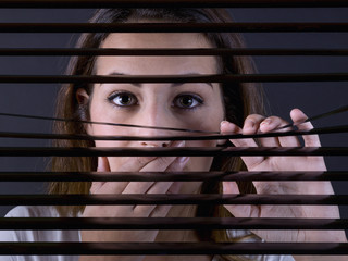 Teen behind a blind, surprised by what she sees.