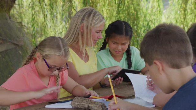 Kids at outdoor school writing in notebooks