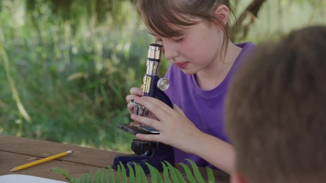 Girl at outdoor school looking through microscope