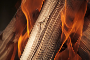 Wooden log placed diagonally burning in fire. Horizontal frame. Close up.