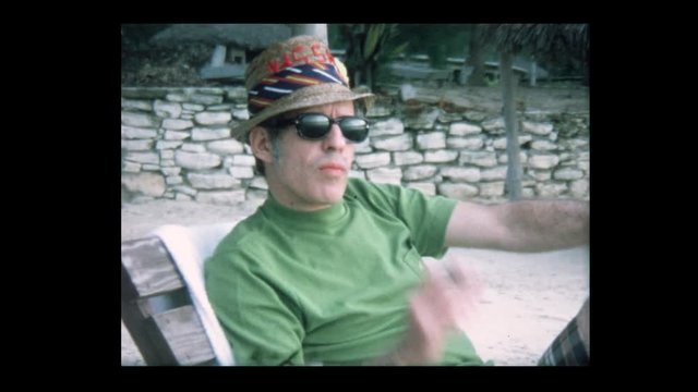 1970 Man smokes cigar with Family on vacation at tropical beach