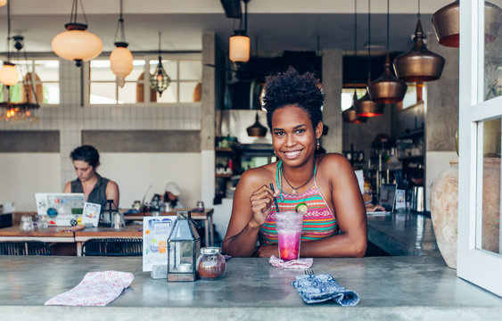 Beautiful Mixed Race Pacific Islander Girl In Vegetarian Cafe For Breakfast With Fresh Mix Smoothie In Glass