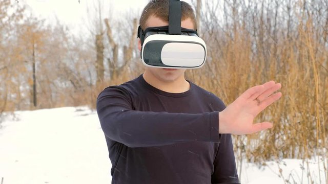 young woman getting experience in using VR-headset outdoor at winter park