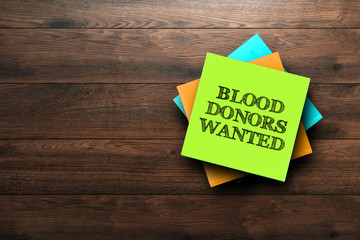 Blood Donors Wanted, the phrase is written on multi-colored stickers, on a brown wooden background. medical concept, strategy, plan, planning.