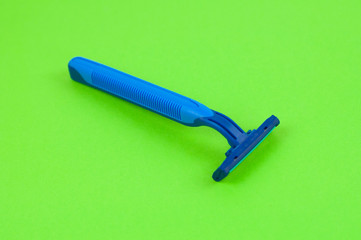 Single new blue plastic disposable razor with two blades on blank green paper