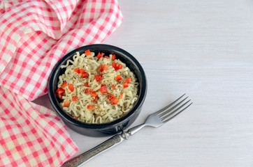 Popular  Asian fast food, instant noodles with red pepper and spice in a ceramic bowl with napkin.. Copy space.