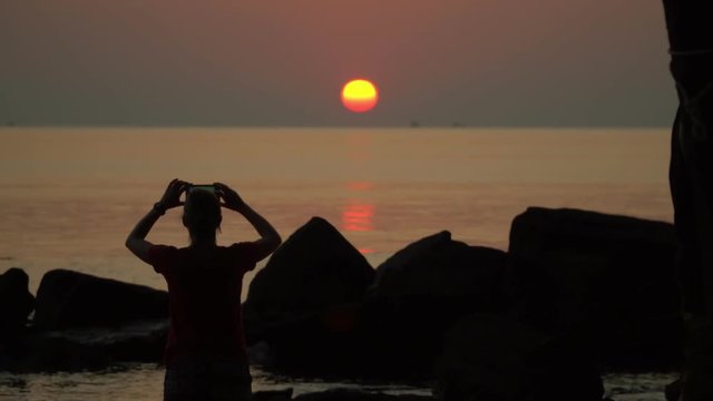 The woman photographs a decline on the island. A decline on the ocean horizon. Tropical island. Vietnam. Tropical Flamenco beach sunset. Silhouette..