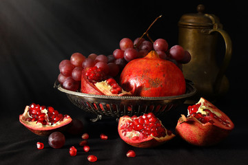 Still life with pomegranates, grapes and brass pitcher