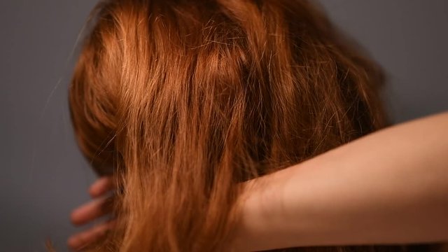 rothaarige Frau  streicht sich die haare aus dem Gesicht und blickt in die Kamera