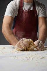 cropped image of chef kneading dough on table