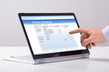 Male's Hand Using Online Banking On Hybrid Laptop