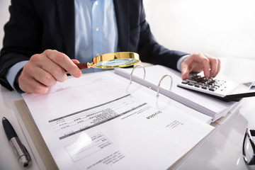 Businessperson Checking Invoice Through Magnifying Glass