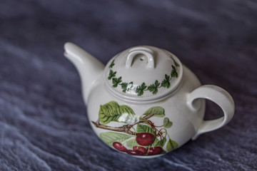 Close-up of a porcelain teapot on an old black marble table. Shallow depth of focus. Concept nostalgia.