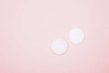 cropped shot of opened jar of cream isolated on pink