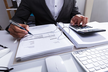 Close-up Of A Businessperson Calculating Bill